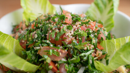 A bowl of delicious fresh Tabbouleh (tabbouli) salad with parsley, mint, tomato, onion, olive oil and lemon juice.