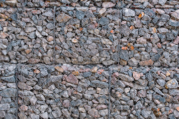 Steel mesh retain stones of gabion wall. Rockfall protection barrier. Gabion wall construction using steel wire mesh basket. Modern wall construction.
