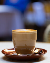 decorated glass of Coffee Piccolo Latte on a white table in a Sydney Cafe NSW Australia