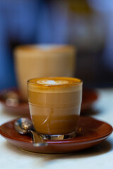 decorated glass of Coffee Piccolo Latte on a white table in a Sydney Cafe NSW Australia
