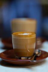 decorated glass of Coffee Piccolo Latte on a white table in a Sydney Cafe NSW Australia