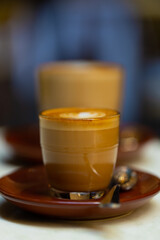 decorated glass of Coffee Piccolo Latte on a white table in a Sydney Cafe NSW Australia