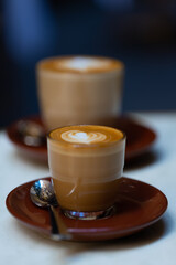 decorated glass of Coffee Piccolo Latte on a white table in a Sydney Cafe NSW Australia