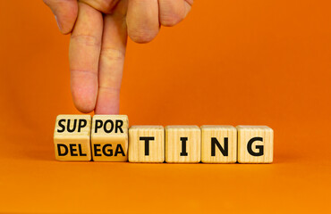 Delegating or supporting leadership style symbol. Businessman turns cubes, changes words supporting to delegating. Beautiful orange background, copy space. Business, delegating or supporting concept.