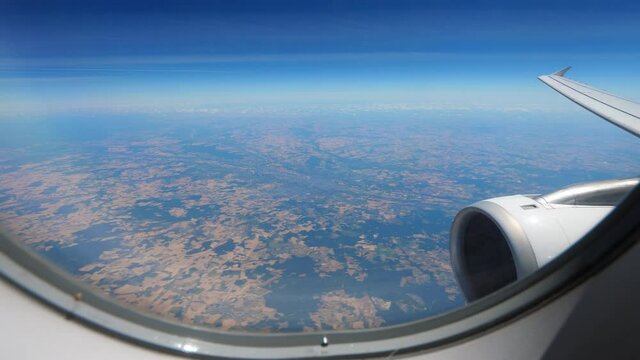Airliner fly at cruise altitude, pass over Centre-Val de Loire region of France. Look down from plane window, time lapse shot. Plain landscape, cultivated land with many agriculture fields seen down
