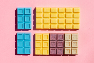 Colorful white chocolate bars ordered on the pink background studio shot