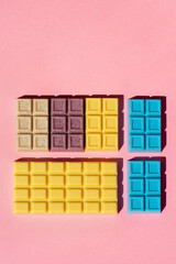 Colorful white chocolate bars ordered on the pink background studio shot