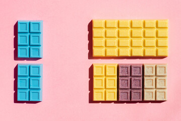 Colorful white chocolate bars ordered on the pink background studio shot