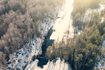 Frozen river in sunny spring day, aerial flight on drone above Karelian nature landscape.