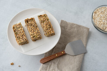 Home made granola bars on a plate next to a linen napkin and serving spatula.