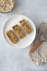 Home made gluten free granola bars on a plate with a bowl of rolled oats in the background.