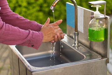 Mujer lavándose las manos con jabón líquido en el parque