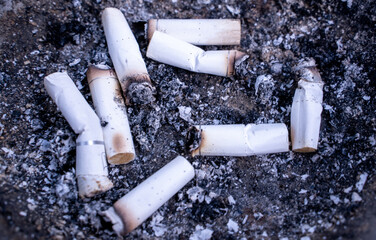 Lots of smoked cigarette buds in a large ash tray on a public area