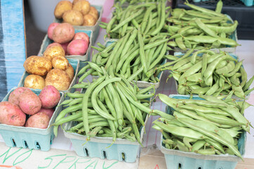 Small potatoes, green beans, and container of peas at the market.