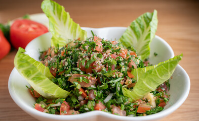 A bowl of delicious fresh Tabbouleh (tabbouli) salad with parsley, mint, tomato, onion, olive oil and lemon juice.