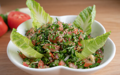 A bowl of delicious fresh Tabbouleh (tabbouli) salad with parsley, mint, tomato, onion, olive oil and lemon juice.