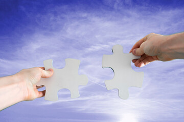 human hands connect two puzzle pieces together, desicion making, sky background