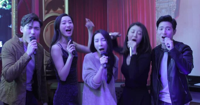 Happy young friends singing karaoke in nightclub,4K