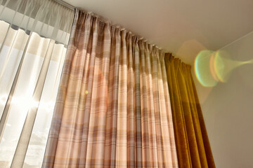 Interior curtains in yellow shades with a glare from the bright sun outside the window