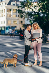 Two businesswoman standing on the street and using laptop