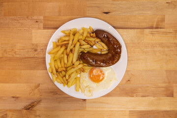 Traditional Portuguese alheira smoked sausage, served with potato fries and a fried egg. Top down.