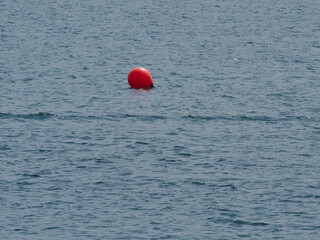 Red round buoy floating on blue sea waves on a sunny day