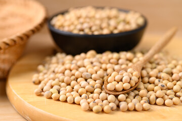 Soybean seeds in spoon and bowl on wooden background