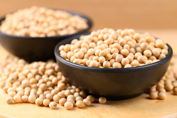 Soybean seeds in black bowl on wooden background