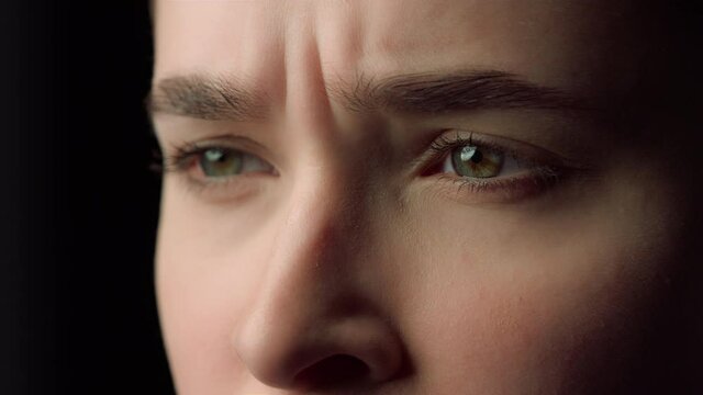 Macro of sad woman face watching unpleasant video indoors.Woman making face