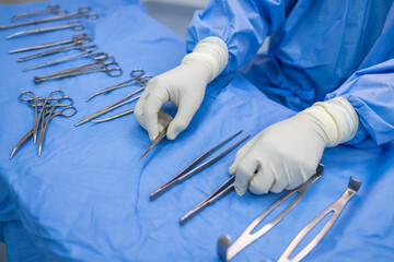 Close up photo selective focus of doctor's hands inside modern operating room in blue surgical gown...