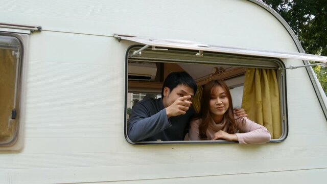 Happy young couple at window of a camper RV van motorhome