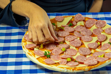 Female hands preparing a homemade cheese and pepperoni pizza.