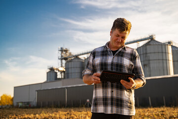 Closeup of man looking at tablet satisfied. Grain silos in background 