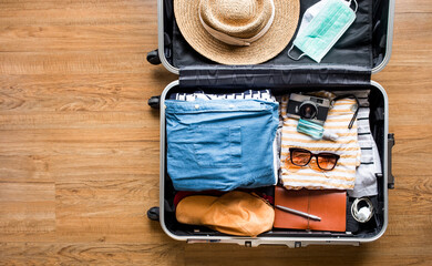  Top view of Luggage,suitcase bag with clothing and mask on wood floor.summer and vacation with...