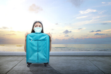 Fototapeta premium Asian woman with a face mask with a suitcase on the dock