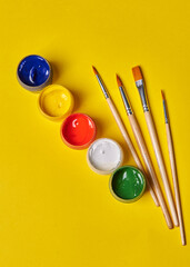 four tassels and colored gouache stands on a yellow background