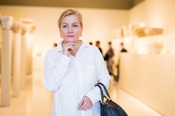 Portrait of senior blonde woman visiting exposition at historical museum
