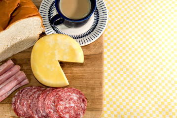 Colonial breakfast served with bread, cheese, ham and salami. Cup with latte.