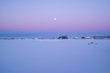 夜明け前の月と農村風景
