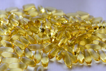 Bunch of omega 3 fish liver oil capsules in pile. Close up of big golden translucent pills texture. Healthy every day nutritional supplement. Top view