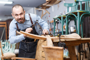 Professional young man carpenter repairing antique furniture in workshop