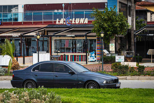 Antalya, Turkey &ndash; April 12 2021:  blue   BMW 5-series e39 parked on the street on a warm summer day against the backdrop of trees, palms