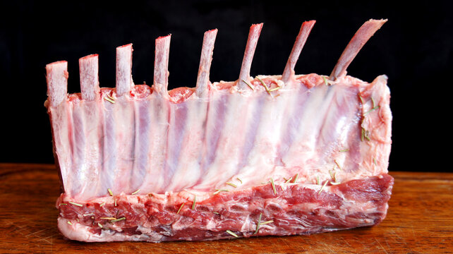 Carr&eacute; de Cordeiro. Raw rack of lamb. Spiced with rosemary and herbs on black background