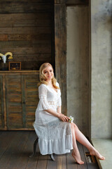 Naklejka premium Morning of the bride. A gorgeous bride, a beautiful woman with long hair in a white robe by the window. The bride before the wedding. Natural beauty and professional makeup.