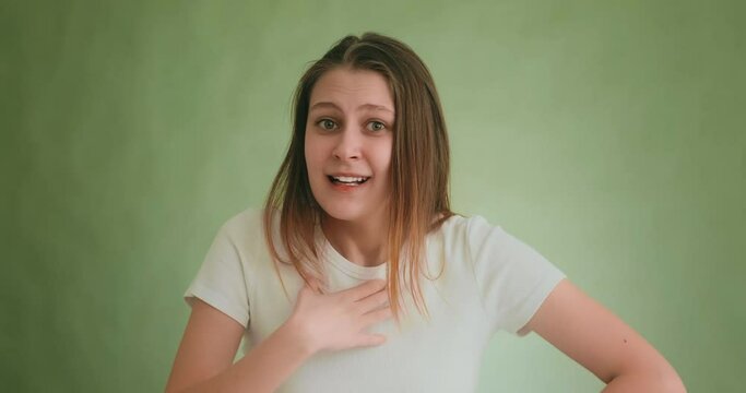 Doubting woman in casual t-shirt tries to understand friend posing for camera on green background at audition closeup slow motion