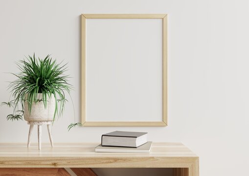 Photo frame mockup on a white wall in the living room, a flower pot and paper placed on a wooden table.3d rendering.