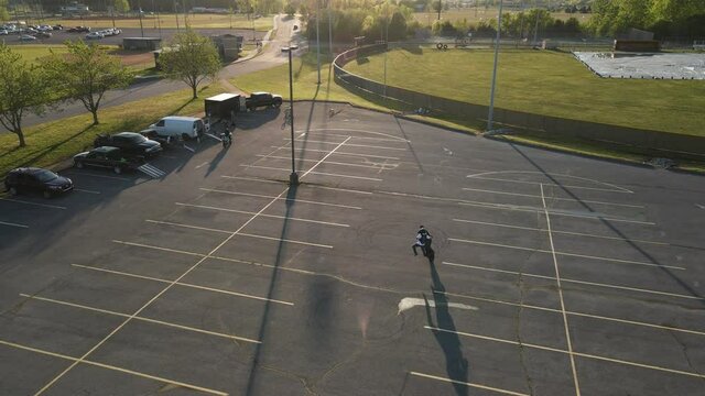 Aerial footage of motorcyclist doing tricks in an empty parking lot