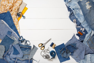 Upcycle old denim garbage. Recycling old jeans. Old blue jeans cut pieces and sewing materials ready for recycling and scissors on white background. Circular economy. Zero waste banner with copy space
