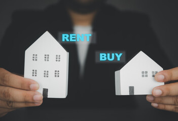 Businessman hand holding white home with text RENT and BUY for customer choice.