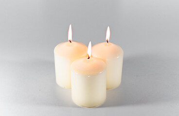 Obraz na płótnie Canvas Three lighted candles on a white background